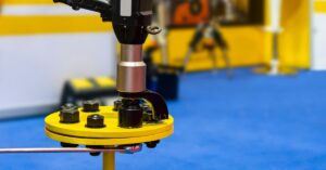An electric torque wrench tightening the bolt and nut on a piece of equipment that is being held on the ground.